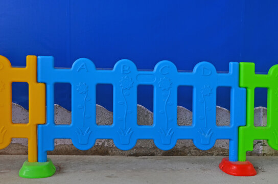 Colored plastic fence with blue background on concrete floor