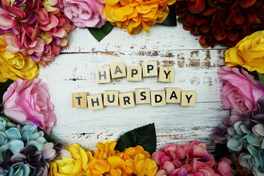 Happy Thursday alphabet letter with colorful flowers border frame on wooden background