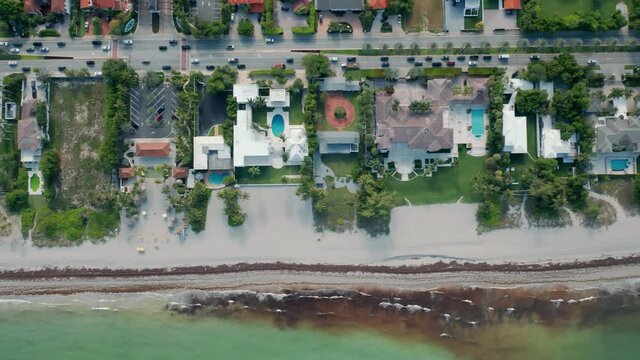 4K aerial for real estate and tourism business. Slow-motion overhead view of lavish nature on tropical island with expensive homes with pools and private white sandy beach. Green clear bay waters, USA