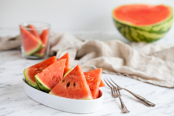 A bowl of watermelon slices with forks on the table.