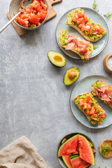 Homemade bread with avocado spread,  chopped tomatoes and herbs. Bread with Parma prosciutto ham. Healthy breakfast concept seen from above. With copy space.