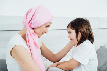 Cancer mother with a pink headscarf tenderly explains the disease to her son