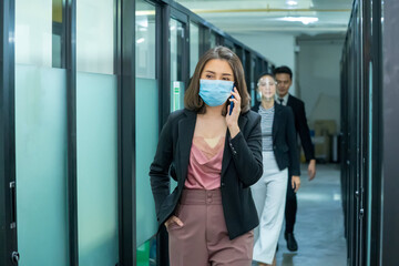 Obraz premium Business workers wearing medical facial mask working as of social distancing policy in the business office during new normal change after coronavirus or post covid-19 outbreak pandemic situation.