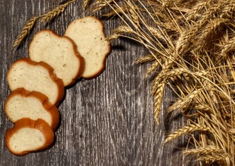 Sliced ​​white wheat bread and ears of wheat lie on a wooden table