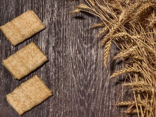 Three wrapped baked spring rolls lie on the table against a background of golden wheat