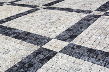 Decorative sidewalk pavement. Tiled floor with gray and black tiles, double-crossed by a diagonal strip of marble viewed at a low angle, full frame background image