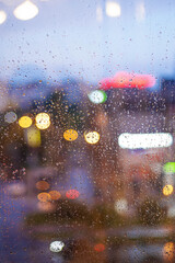 window with raindrops and defocused multicolored lights in the evening