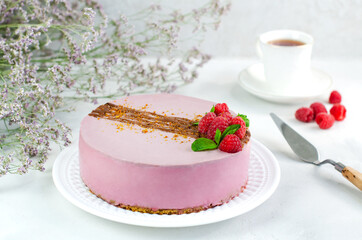 Raspberry cake on a white plate, on a white background. Close-up. Pistachio filling sprinkled with caramel. Vegan, vegetarian dessert