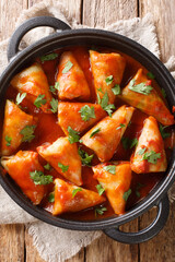 cabbage rolls with meat and rice with tomato sauce and parsley close-up in a bowl on the table. Vertical top view from above