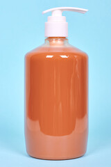Orange liquid soap bottle, plastic dispenser. Isolated on blue background.