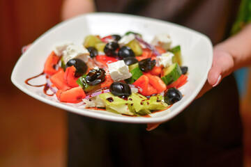 Greek salad. Tasty and healthy vegetarian meal. Eating out in restaurant, service.