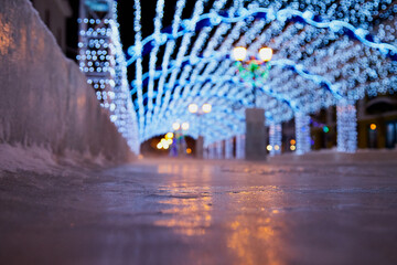 Decorated Christmas tunnel and ice rink in night street of the city