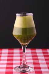 Glass of cold drink with fruit on a dark black background, isolated, close-up.