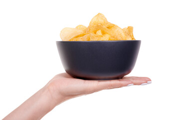 Hand with golden potato chip in dark bowl, isolated on white background.