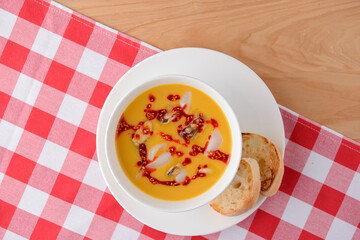 Hot and sour soup with shrimps and clams. Sea food soup with sauce served in a white bowl over light rustic wooden table