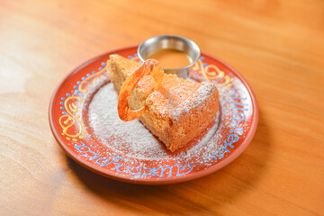Vanilla cake topping with white powdered sugar. Served on a ceramic plate over light wooden background.