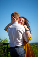 A date between a young girl and a guy on a Sunny summer day. Young beautiful couple on walk in the city. Man and woman at a love meeting with hugs and kisses outdoors