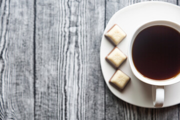 White cup with coffee on a white saucer on a gray wood background