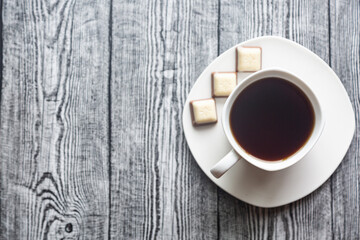 White cup with coffee on a white saucer on a gray wood background