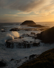 Obraz premium Water from the rough sea being smashed against the cliffs in Australia at sunset
