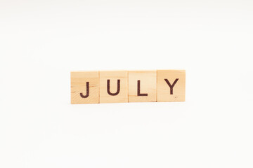 Word JULY made of wooden blocks on white background. Month of year