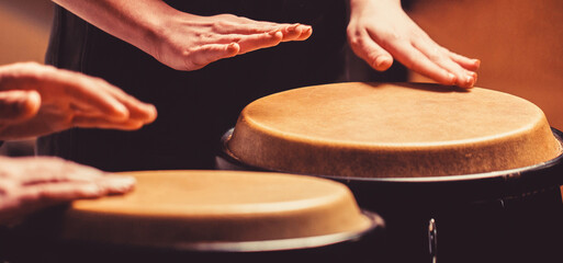 Close up of musician hand playing bongos drums. rum. Hands of a musician playing on bongs. The...