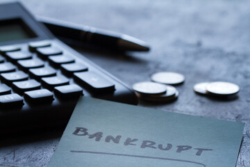 Financial failure, bankruptcy concept. Coins, calculator, pen and inscription bankrupt on dark...
