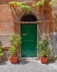 vintage house facade with green arched door and flowerpots, Trastevere old neighborhood, Rome Italy