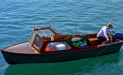 Obraz premium fisherman on a motor, wooden boat with a fishing rod