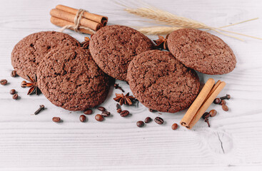 composition of oat chocolate cookies decorated with coffee beans, star anise, cinnamon sticks, cloves, wheat on a white wooden table background  with copy space. image design for cafe menu layout