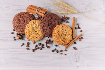 Fresh baked oat and oatmeal cookies decorated with coffee beans, star anise, cinnamon sticks, cloves, wheat on a white wooden table background with copy space. Image design for cafe menu layout