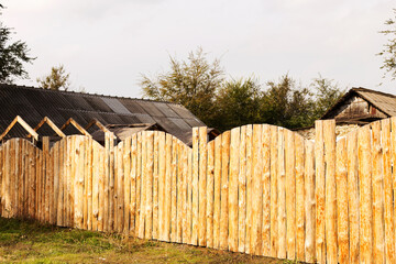Rural landscape with a wooden fence around the old house