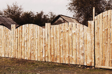 Fototapeta premium Rural landscape with a wooden fence around the old house