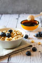 Honey rings with blueberries and honey in a bowl on the table wooden background. Copy space. Flat lay. Vertical orientation.