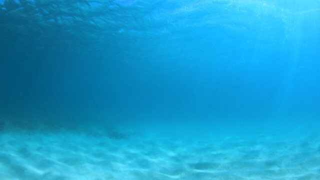 Underwater background of blue sea water and ocean floor 