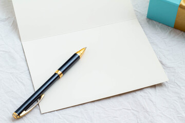 白紙のカードと金色のリボンの青いギフトボックスとボールペン