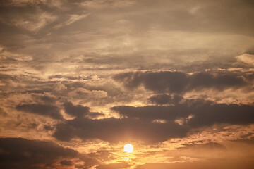 Sunset sky in evening. The sun in In the lower middle of frame and golden light on clouds.