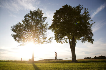 junger Mann auf der Slackline im Sonnenuntergang