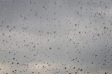 water rain drops on glass surface window with cloudy background. Copy space. Natural Pattern.