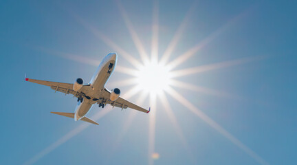 Naklejka premium Comercial airplane take off from airport runway against the backdrop of a scenic evening sky with sun rays.