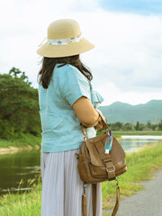 Mini portable alcohol gel bottle to kill Corona Virus(Covid-19) hang on leather shoulder bag of woman standing outdoor roadside.New normal lifestyle.Health care concept.Selective focus on alcohol gel