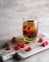 Jelly dessert with berries in glass on old wooden cutting board, sweet colorful layered pudding,...