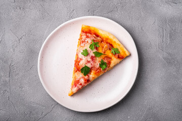 Hot pizza slice with mozzarella cheese, ham, tomato and parsley on plate, stone concrete...