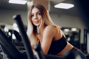Fototapeta na wymiar Fit curvy young blonde woman training in a cardio zone in a gym