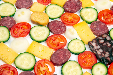 sliced ​​pieces of sausage, salami, cheese, cucumber and tomato. fast food. ingredients for pizza. calories and diet