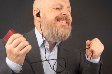 bearded business man enjoys listening to his favorite music through an audio player in small headphones. audiophile and music lover. music and hi-fi sound