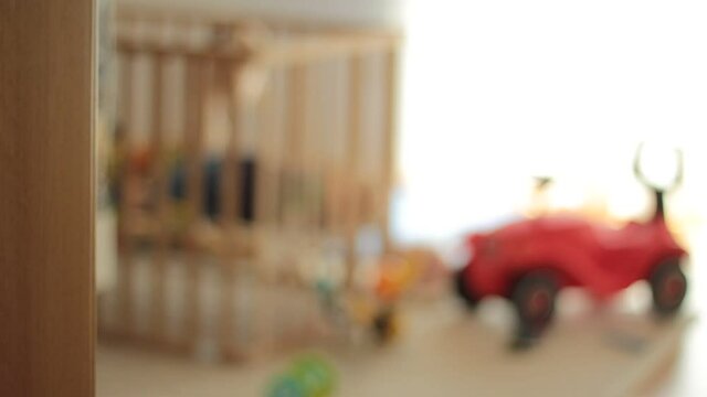 Small baby in a wooden baby cot. Out of focus.