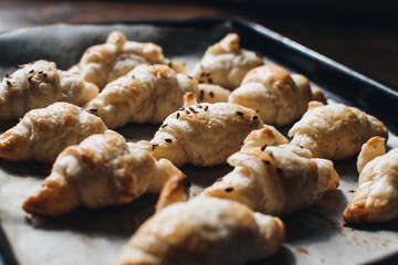 Freshly baked homemade croissants on wooden table, selective focus Fresh out of the oven. Breakfast or brunch concept.