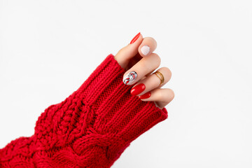 Woman's hand in sweater with red manicure on gray background