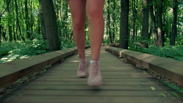 A girl with slender legs in short shorts runs in the park. Summer park.
